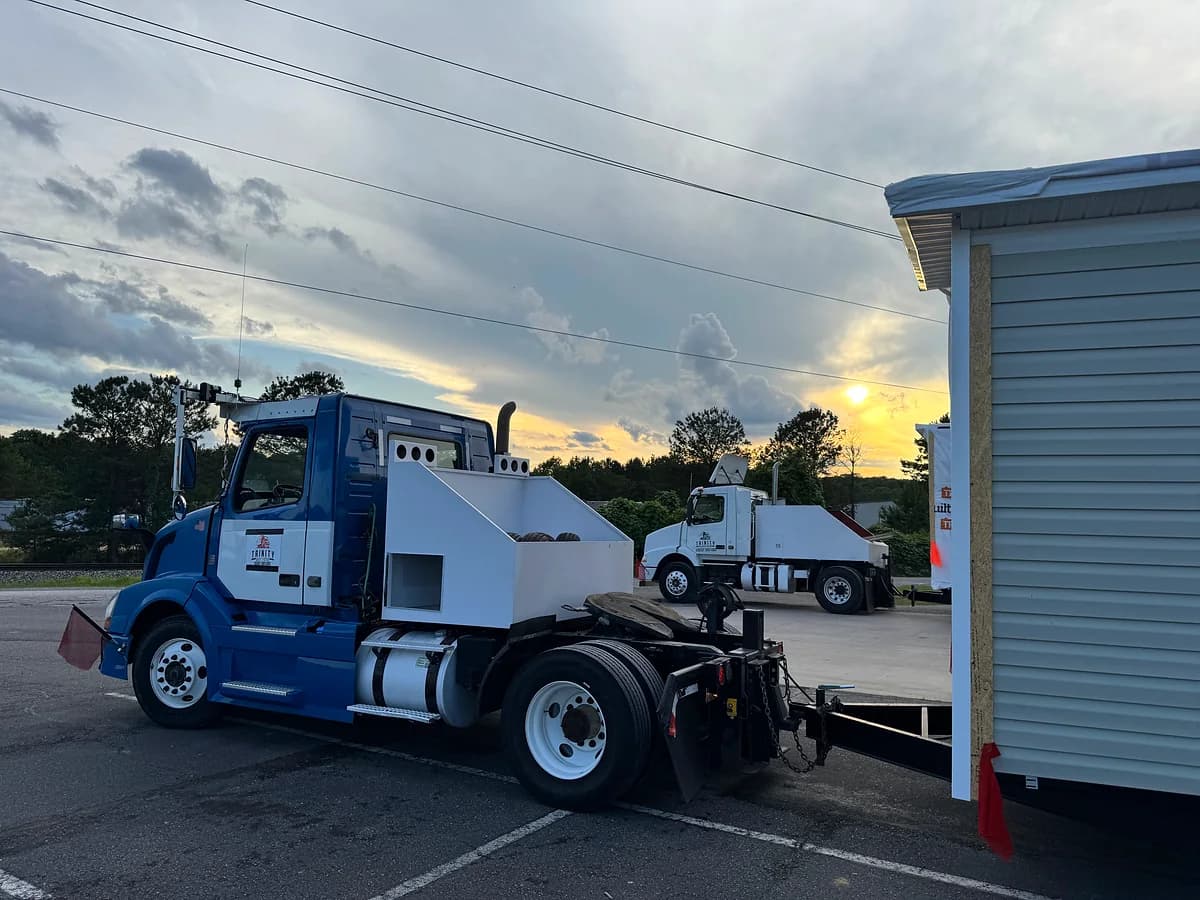 Trinity blue Volvo truck with mobile home flatbed at sunset