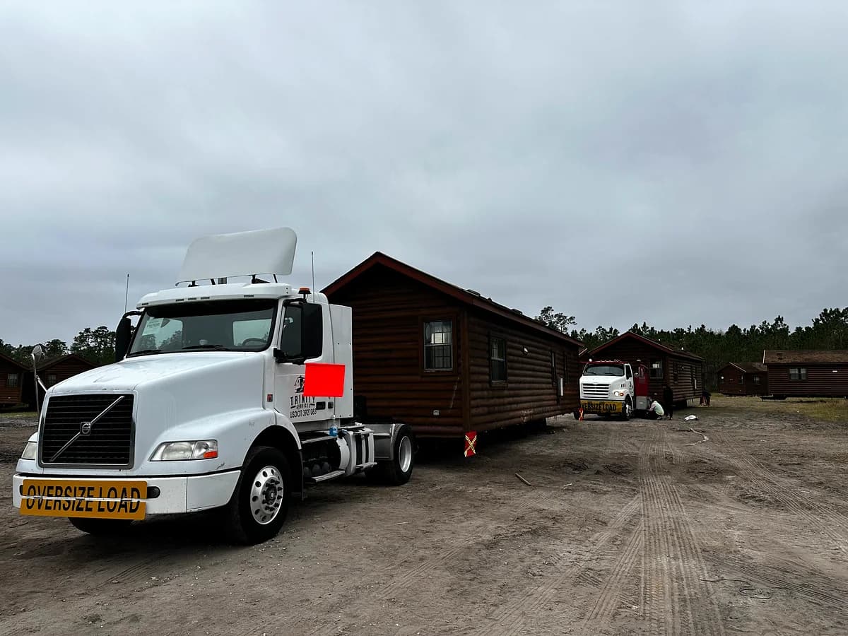 Trinity Volvo with OVERSIZE LOAD banner pulling a log cabin style mobile home